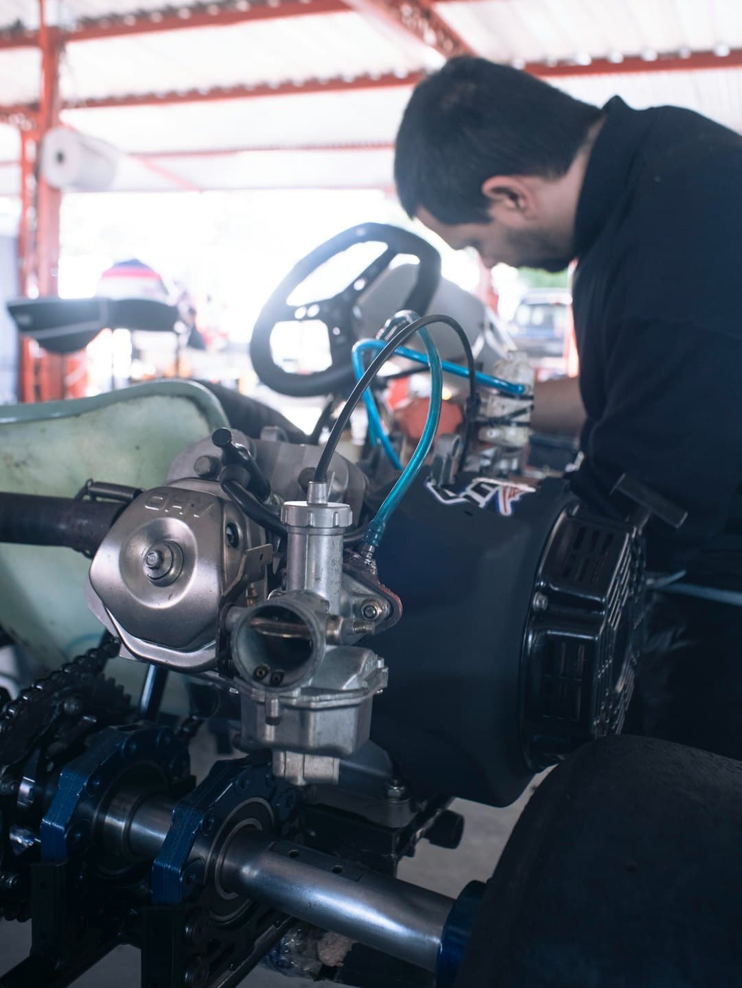 Mechanik pracuje na motoru motokáry v dílně.