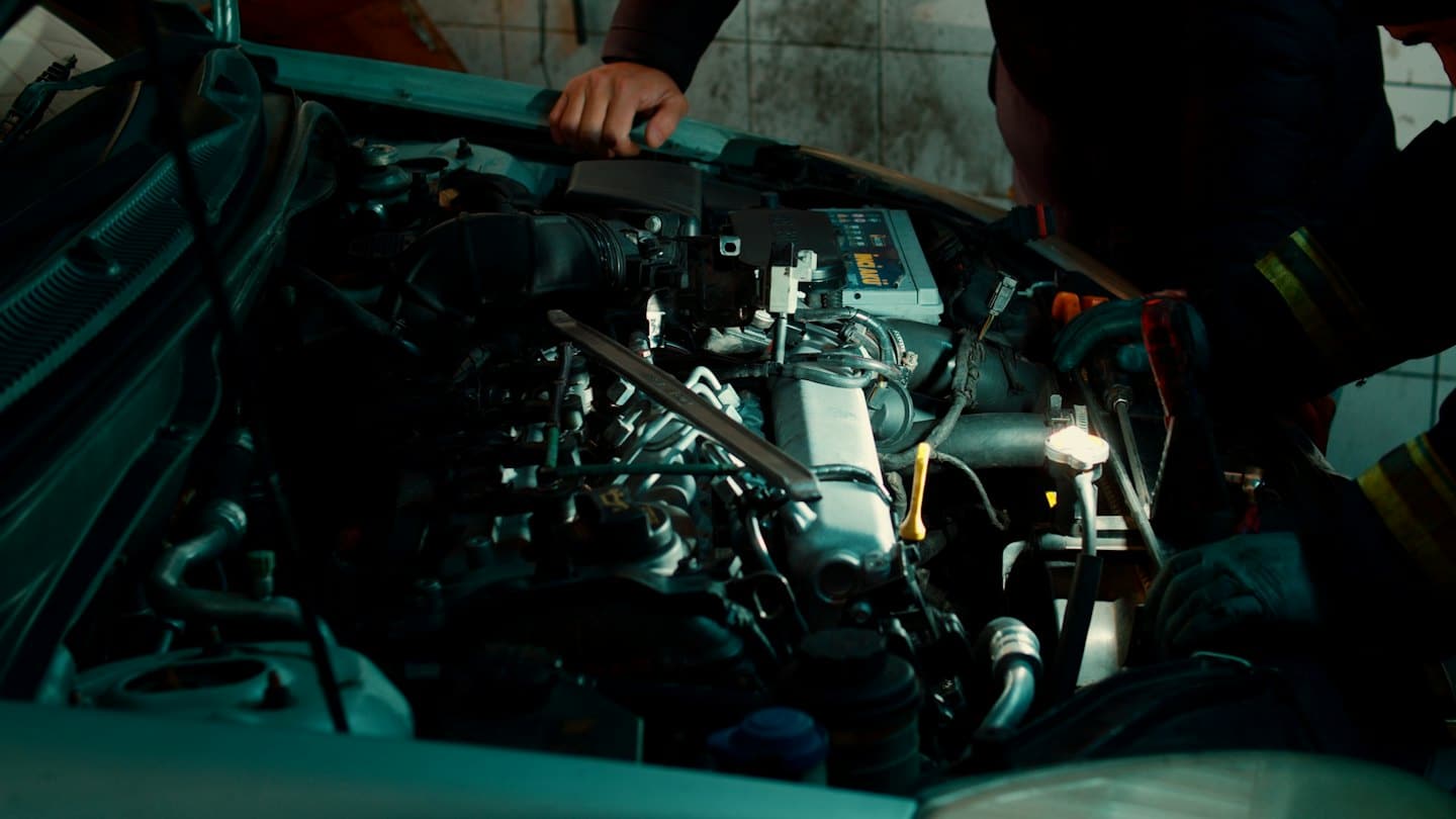 Mechanikovy ruce pracující na motoru auta v garáži.